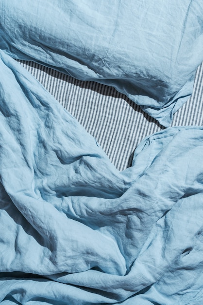 Flatlay of blue linen bed cloths and pillow