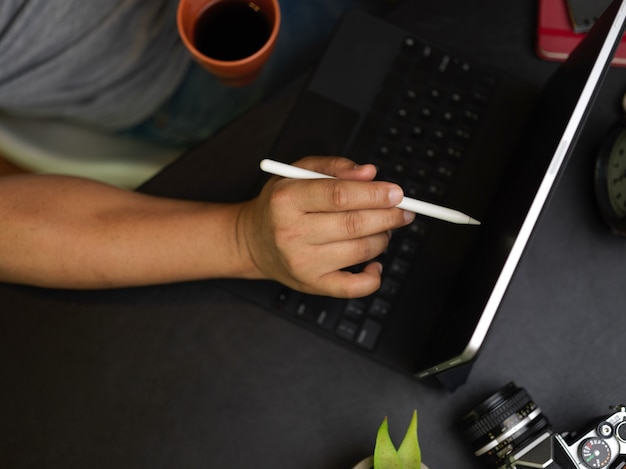 Uomo d'affari flatlay che lavora su tablet bevendo caffè al mattino scrivania nera sfondo nero