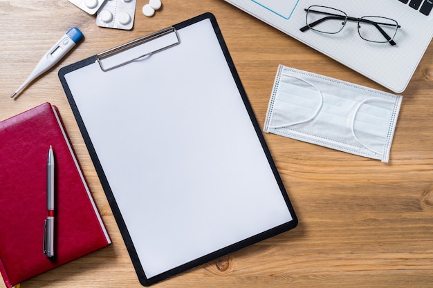 Photo flatlay doctor workplace with mask and with notepad mock up