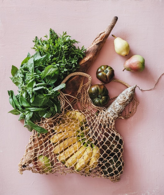 Flatlay экологически чистой сумки со свежими ингредиентами на розовом фоне