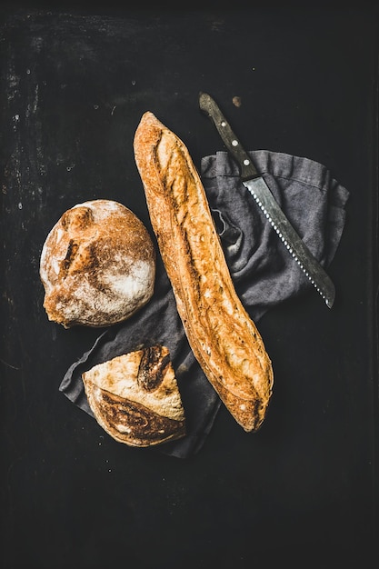 Flatlay of freshly baked baguette and loaf over black background