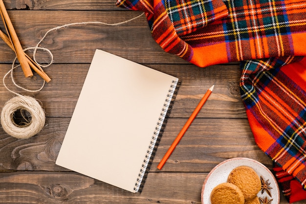 Flatlay herfst samenstelling. de vrouwen vormen rode sjaal, document blocnote met lege pagina, pen, koekjes