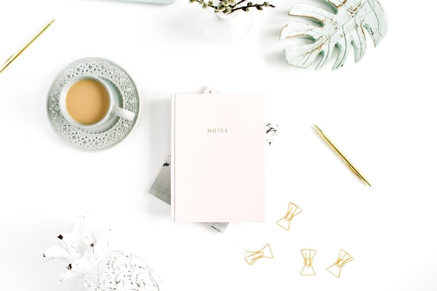 Flatlay of home office desk table. Workspace with pale pastel pink notebook and decorations. Flat lay, top view.