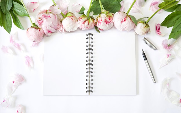 Flatlay office desk Workplace with peonies petals and block note Plan writing concept