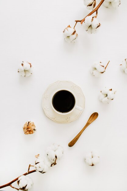 Flatlay van koffiekopje, houten lepel en wattenstaafjes op wit oppervlak