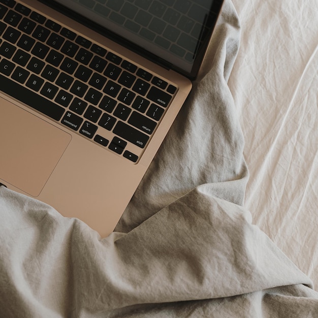 Flatlay van laptopcomputer in bed met grijs verfrommeld beddengoed Werk thuis freelance concept