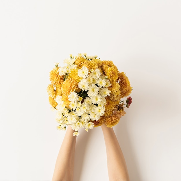 Flatlay van vrouwelijke handen met geel en gember vallen wilde bloemen boeket op wit