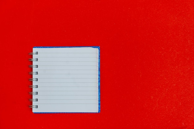 Above flatlay view photo of open clear with empty space copybook on spiral isolated red backdrop