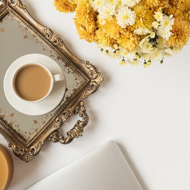 Flatlay vrouwelijke minimale werkruimte met laptop, koffiekopje en mooi bloemenboeket op witte tafel. Bovenaanzicht