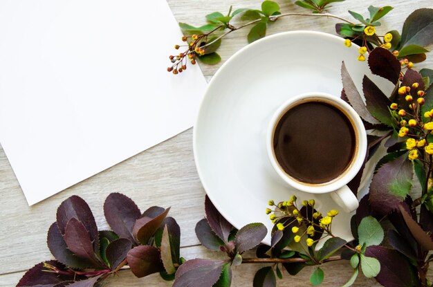Плоский лист с чашечкой кофе на макете тарелки и белым пустым листом, обрамленным ветвями