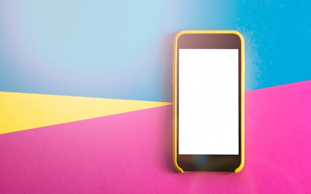 Flatlay with smartphone on three tone solid color yellow, violet and light blue background