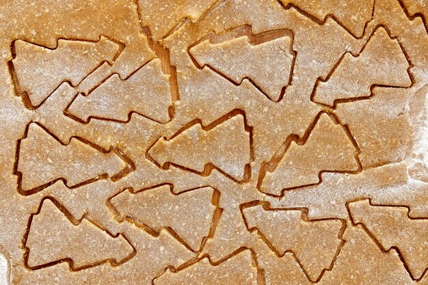 Flatted dough for christmas gingerbread cookies with cutted biscuits a shape of christmas tree