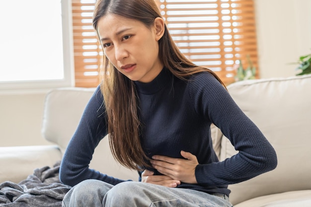 胃の痛みの鼓腸アジアの若い女性の女の子の手は、食物中毒腹痛と結腸の問題に苦しんでいます胃炎または下痢患者の腹腹部または炎症の概念