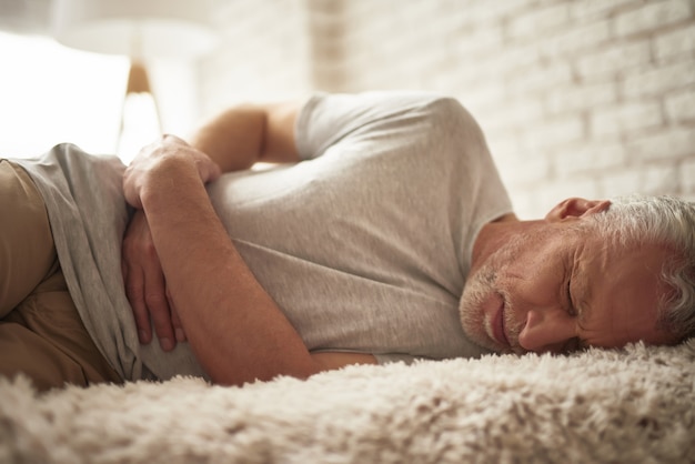 Flauwvallen oude man in bed Buikpijn Maagpijn.