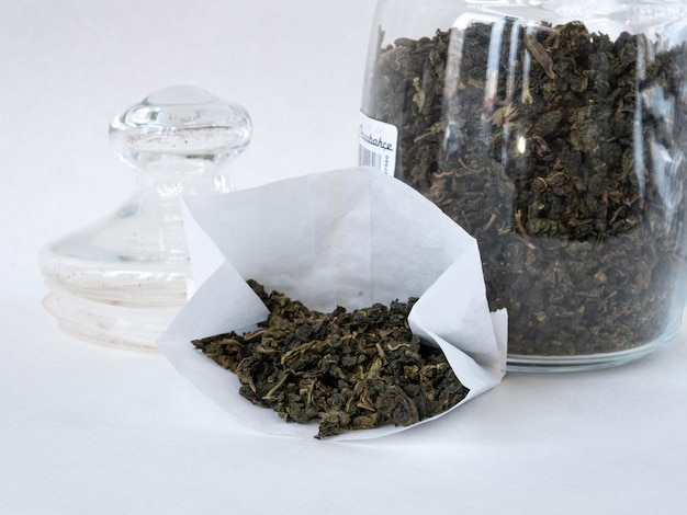 Flavored green tea in a glass jar and in a white paper bag Closeup