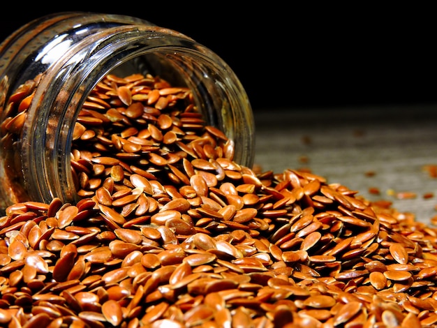 Flax seeds are poured from a glass jar.