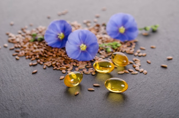 Flax seeds , beauty flower and oil in caps on a grey . phytotherapy.