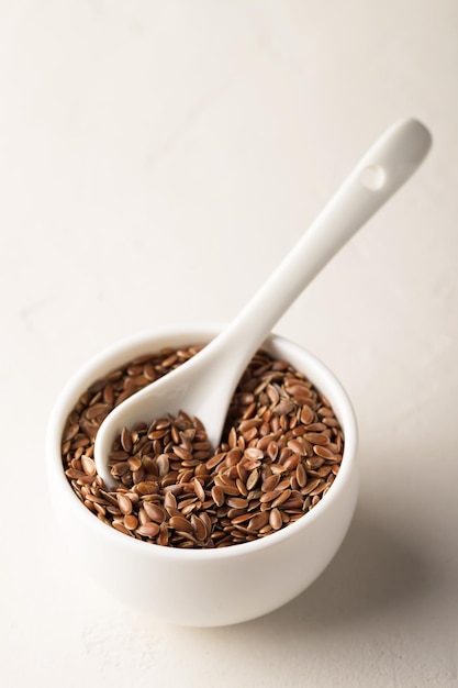 Flax seeds in a bowl on a light background. Selective focus. Close-up, copy space.