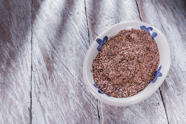 Flax seeds in bowl on old wood