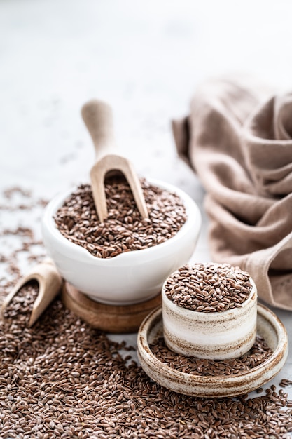 Flax seeds in a ceramic bowl with a wooden spoon. Organic healthy food. Vertical photo