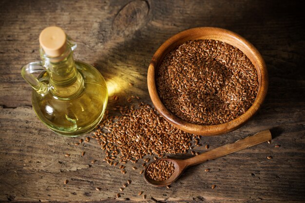 Flax seeds and linseed oil in a glass jug on a wooden table