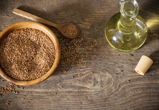 Flax seeds and linseed oil in a glass jug on a wooden table