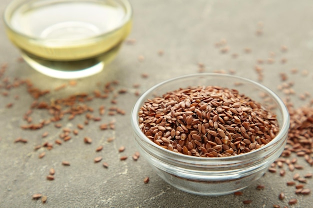 Flax seeds and oil in bottle on grey background