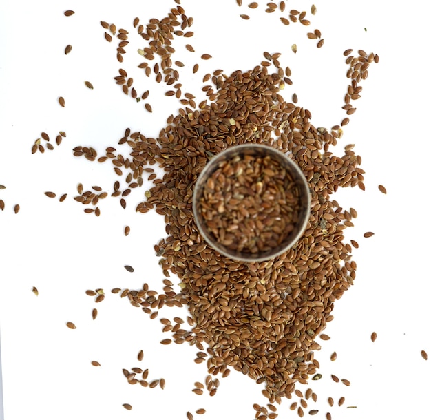 flax seeds in a small metal cup on white background