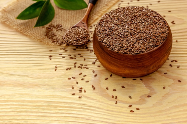 Foto semi di lino in un cucchiaio e una ciotola con una bottiglia di olio di semi di lino