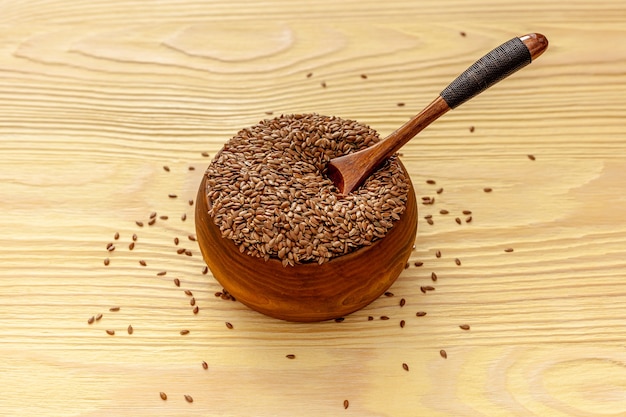 Flax seeds in a spoon and bowl with a bottle of flaxseed oil