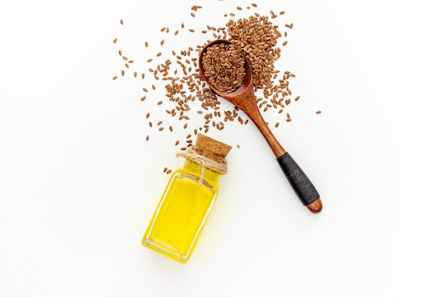 Flax seeds in a spoon and bowl with a bottle of flaxseed oil