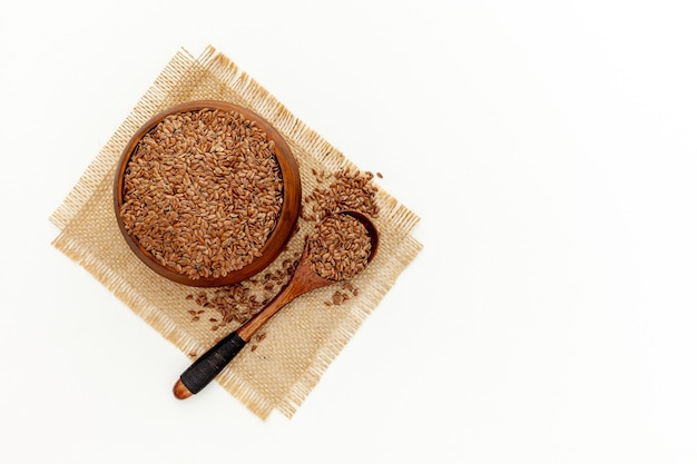 Semi di lino in un cucchiaio e una ciotola con una bottiglia di olio di semi di lino