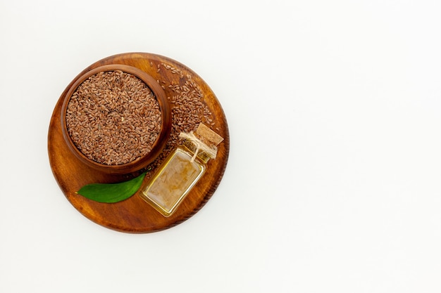 Foto semi di lino in un cucchiaio e una ciotola con una bottiglia di olio di semi di lino