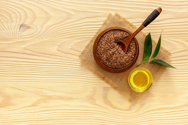 Flax seeds in a spoon and bowl with a bottle of flaxseed oil