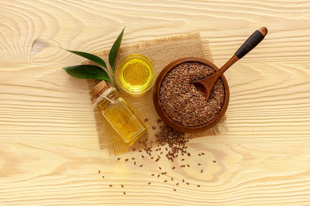 Flax seeds in a spoon and bowl with a bottle of flaxseed oil