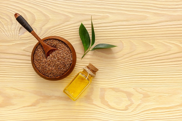 Flax seeds in a spoon and bowl with a bottle of flaxseed oil