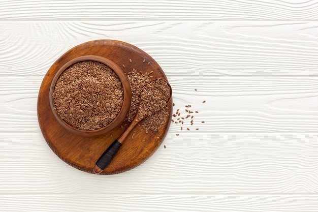 Flax seeds in a spoon and bowl with a bottle of flaxseed oil