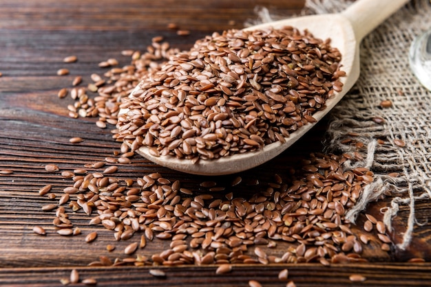 Flax seeds in wooden spoon on wooden background