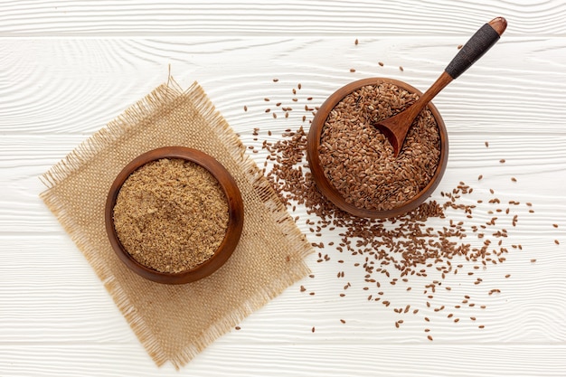 Flaxseeds in a spoon and bowl with a bottle of flaxseed oil and flaxseed flour