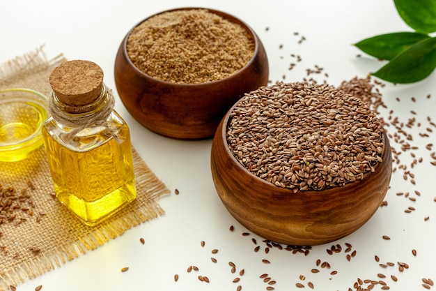 Flaxseeds in a spoon and bowl with a bottle of flaxseed oil and flaxseed flour