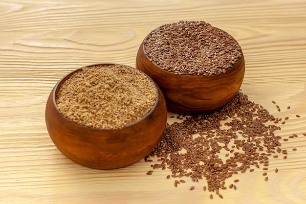 Flaxseeds in a spoon and bowl with a bottle of flaxseed oil and flaxseed flour
