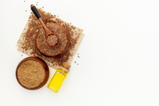 Flaxseeds in a spoon and bowl with a bottle of flaxseed oil and flaxseed flour