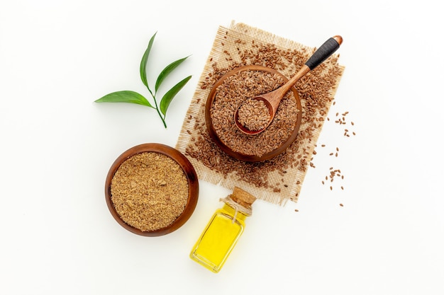 Photo flaxseeds in a spoon and bowl with a bottle of flaxseed oil and flaxseed flour