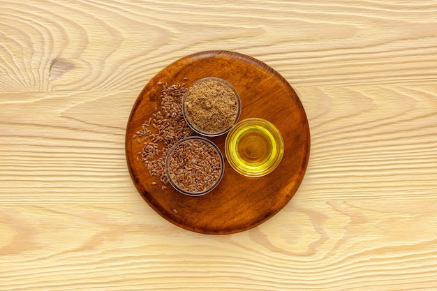 Flaxseeds in a spoon and bowl with a bottle of flaxseed oil and flaxseed flour