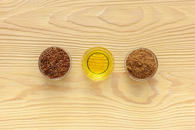 Flaxseeds in a spoon and bowl with a bottle of flaxseed oil and flaxseed flour