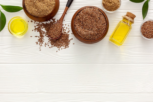 Foto semi di lino in un cucchiaio e una ciotola con una bottiglia di olio di semi di lino e farina di semi di lino