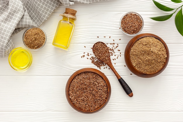 Flaxseeds in a spoon and bowl with a bottle of flaxseed oil and flaxseed flour