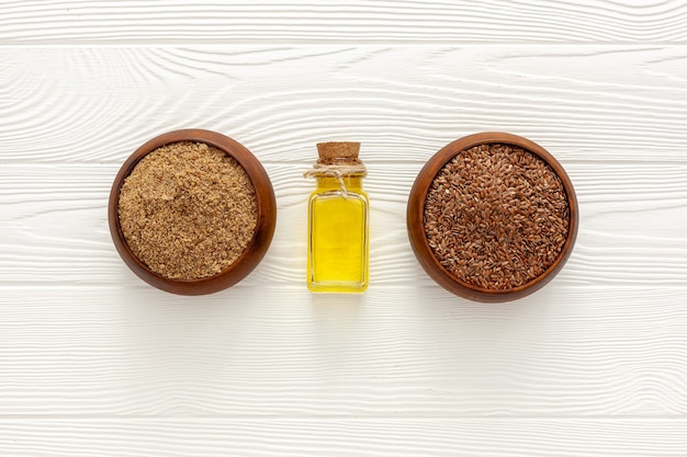 Flaxseeds in a spoon and bowl with a bottle of flaxseed oil and flaxseed flour