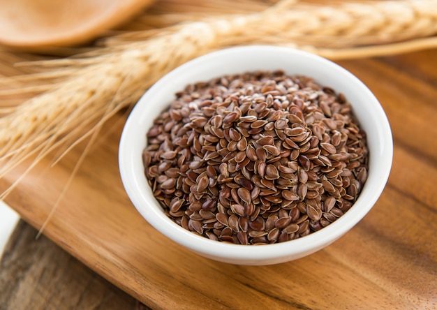 Flaxseeds in white bowl on wood table