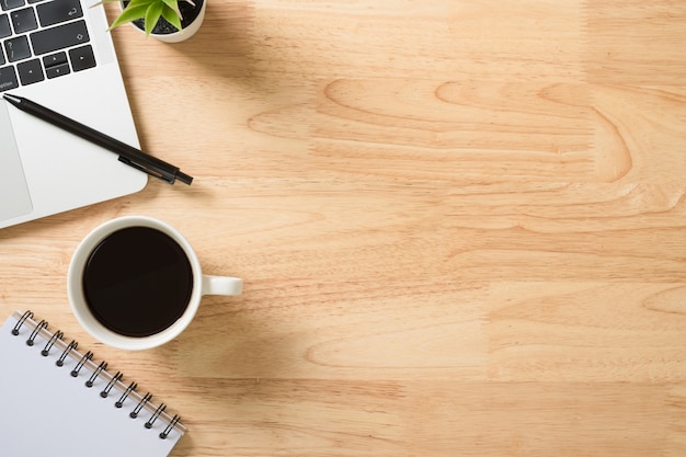 Flay lay, bovenaanzicht kantoor tafel bureau met laptop, toetsenbord, koffie, pen en groene plant